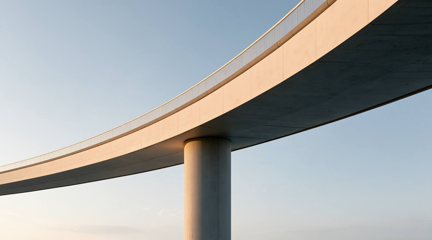 Curved concrete bridge deck resting on a single column against the sky